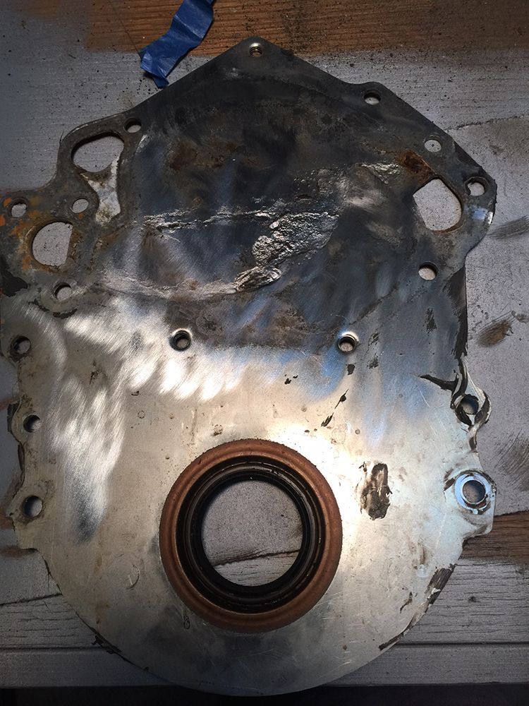Engine timing cover with oil seal, metal surface showing wear and damage