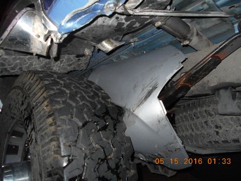 1996 Ford F-250 - Underside view of a truck, focusing on the rear tire and damaged body panel.