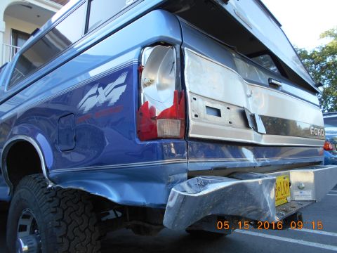 1996 Ford F-250 - This 1996 Ford F-250 shows damage to its rear, including a broken taillight and dented bumper, and is fitted with a camper shell.
