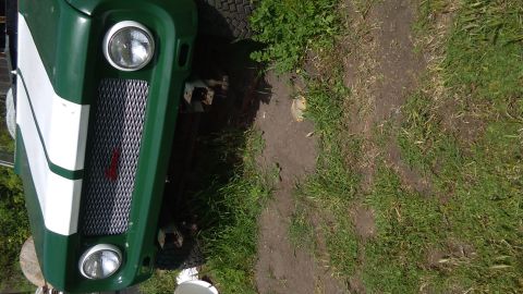 1991 Ford Bronco - The front of a green and white striped SUV is visible, a chrome grille and round headlights.