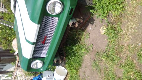 1991 Ford Bronco - Front view of a green vehicle's grille and headlights, with a white stripe on the hood.