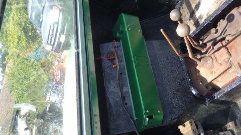 1991 Ford Bronco - The interior of a vehicle reveals a green storage unit and a manual transmission shifter, with another vehicle visible through the window.