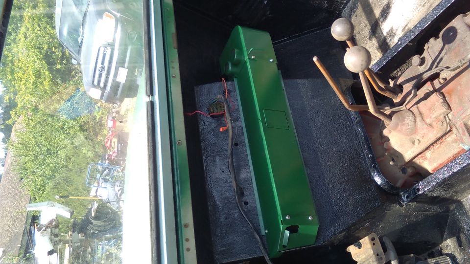 Interior view of a vehicle showing a green storage box and a manual gear shifter