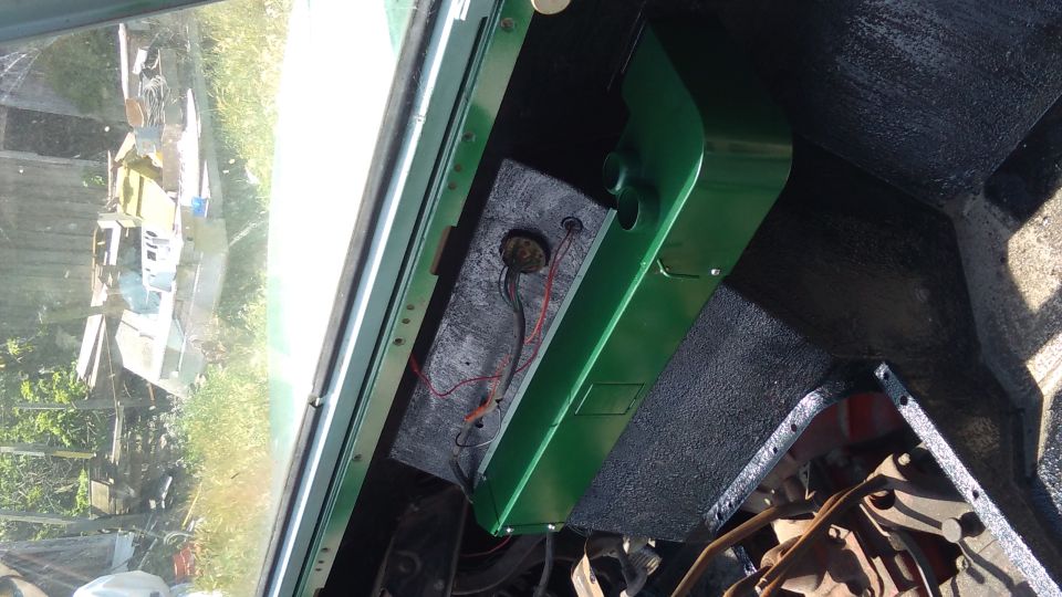 Vehicle interior showing a green panel with wiring and a circular opening
