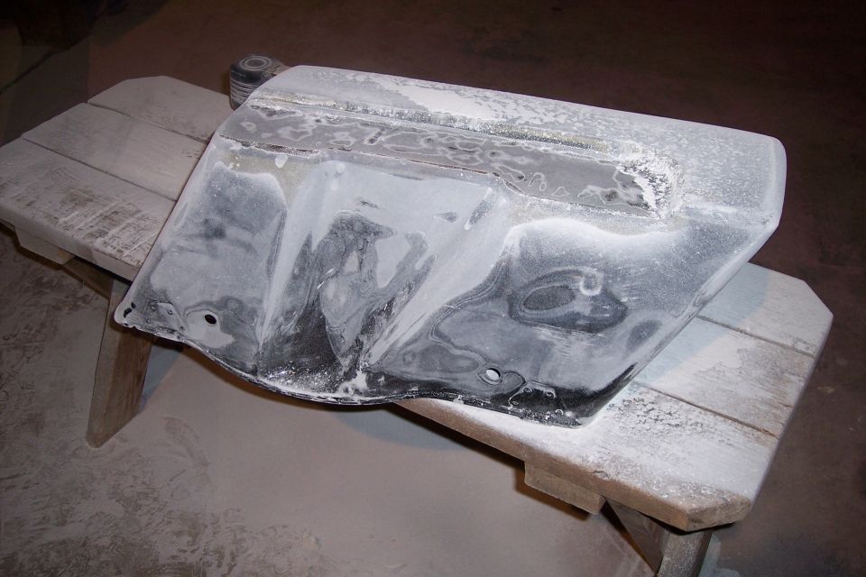 Motorcycle saddlebag covered in sanding dust, sitting on a wooden bench