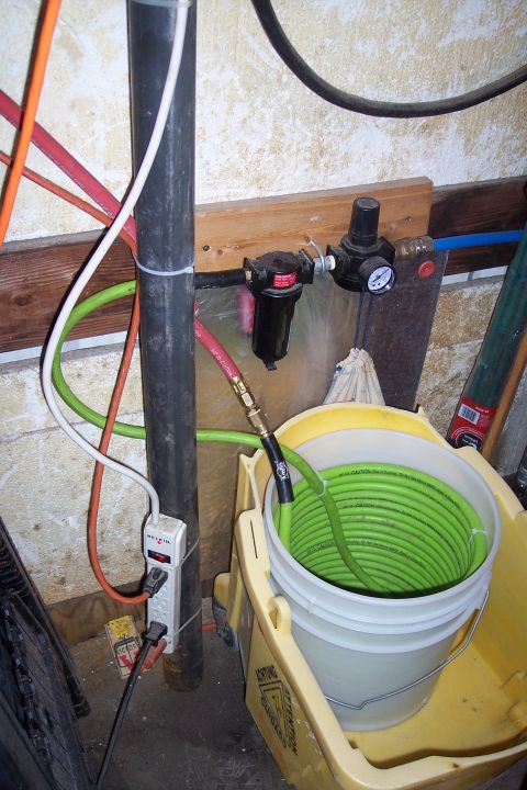 1990 Ford Bronco - Air compressor regulator and filter assembly with coiled hose in a bucket.