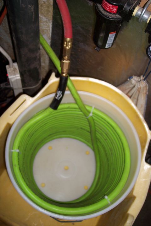 1990 Ford Bronco - An air compressor hose is coiled inside a bucket, connected to a red hose and an air filter.