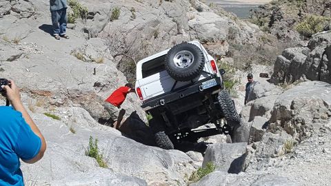 1979 Ford Bronco - A white 1978 Ford Bronco navigates a challenging rocky off-road path with assistance from a person pushing.
