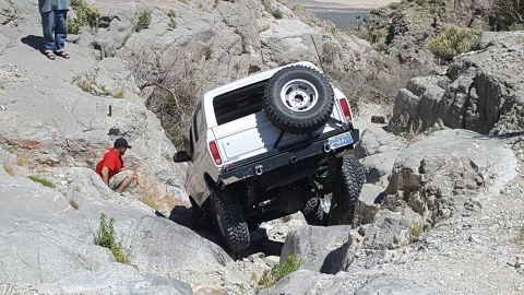 1979 Ford Bronco - A white 1979 Ford Bronco tackles a challenging rocky terrain, demonstrating its off-road capabilities.