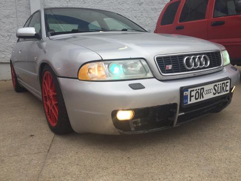 2001 Audi S4 - A silver 2001 Audi S4 sedan is parked in front of a red SUV, displaying a custom license plate.
