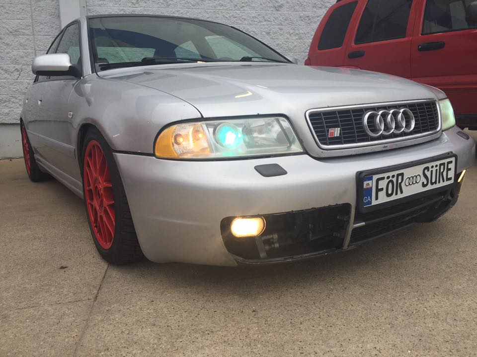 Silver 2001 Audi S4 sedan with red wheels, front view, showing custom license plate and aftermarket front bumper