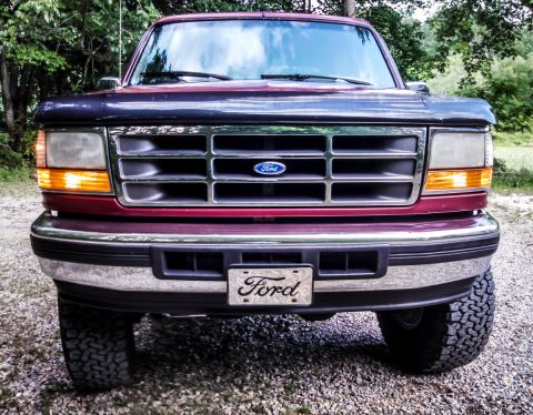 1995 Ford Bronco - Front view of a maroon Ford Bronco with a chrome grille and bumper.