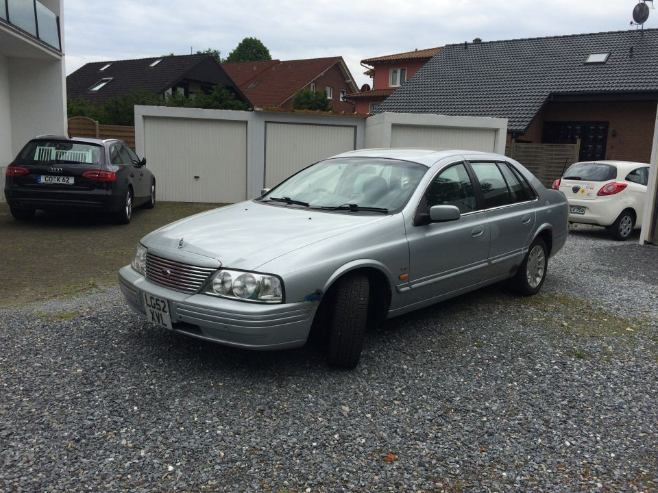 Silver sedan with chrome grille and quad headlights, parked on gravel. License plate LG52 XVL