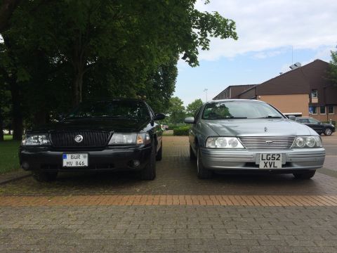 1999 Ford Fairlane - A silver Ford sedan and a black Mercury Grand Marquis are parked side-by-side, both facing the camera.
