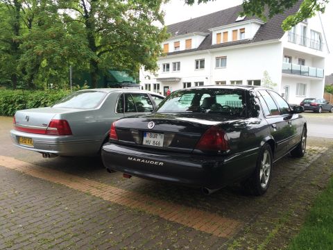 1999 Ford Fairlane - Two sedans, a black Mercury Marauder and a silver sedan, are parked side-by-side in front of a building.