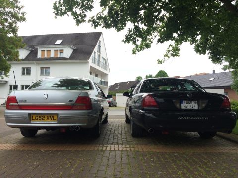 1999 Ford Fairlane - A silver sedan and a black Mercury Marauder are parked next to each other, their rear profiles.