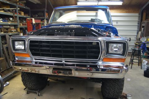 1979 Ford Bronco - Front view of a 1979 Ford Bronco in a garage, hood is open for service.
