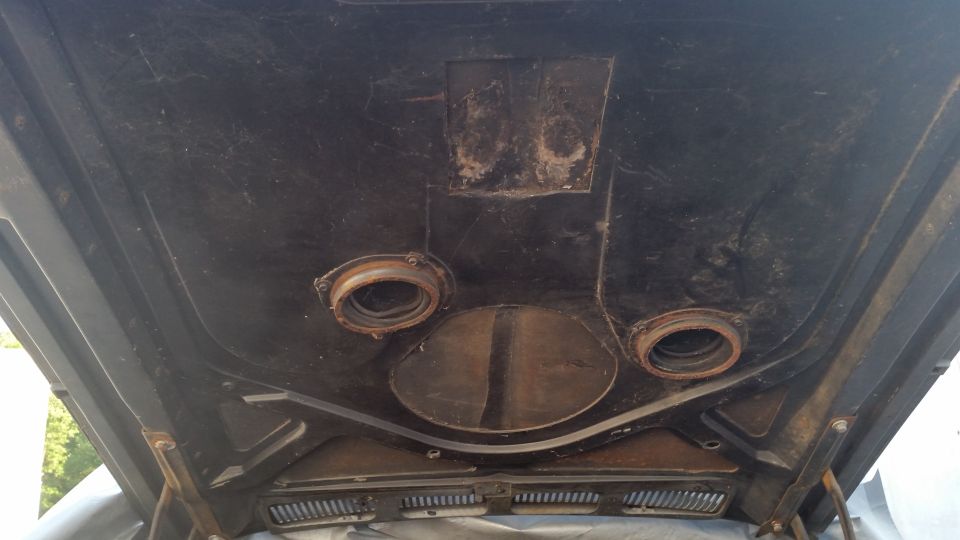 underside of car hood with two circular openings and a central oval vent