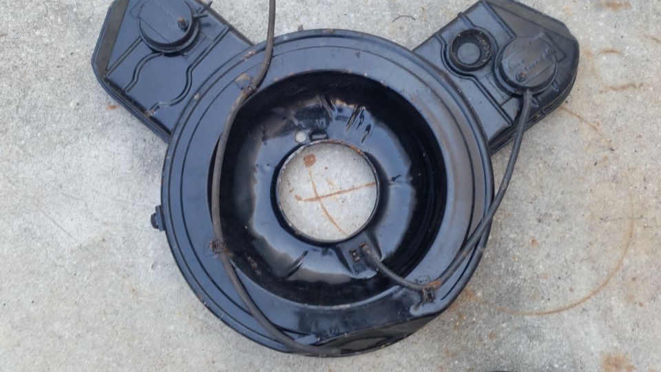 Black air cleaner assembly with two circular lids on top, resting on concrete