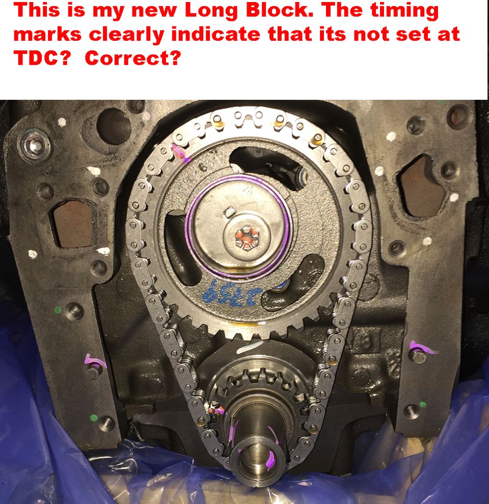 Engine timing chain and gears with purple marks on a dark metal block, Supermotors.net logo at bottom right