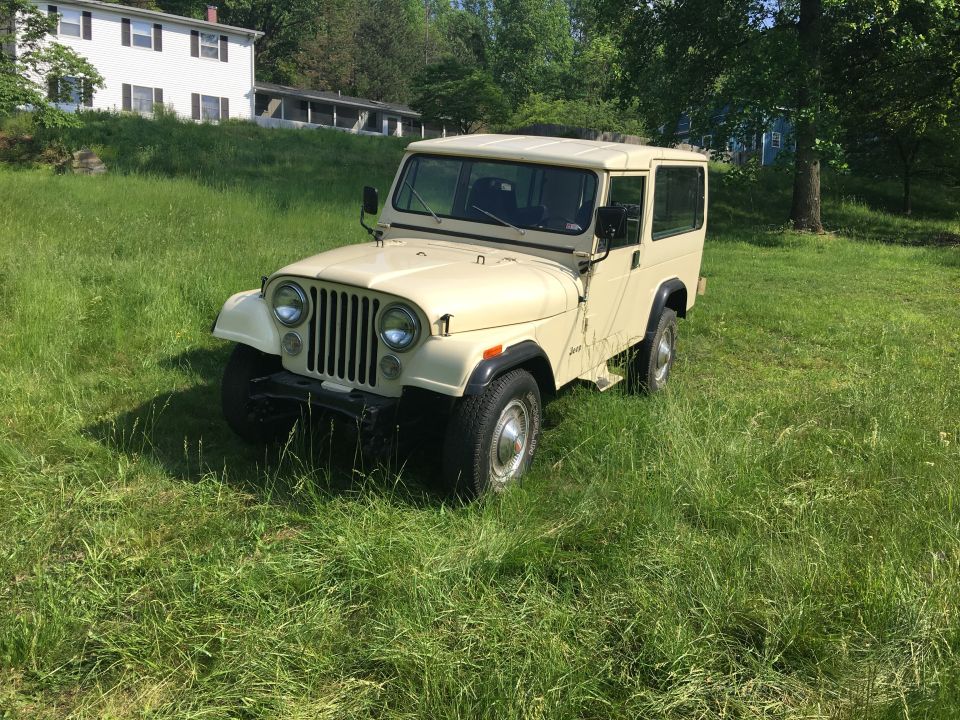Tan 1986 Jeep CJ-8 Scrambler parked in a grassy field