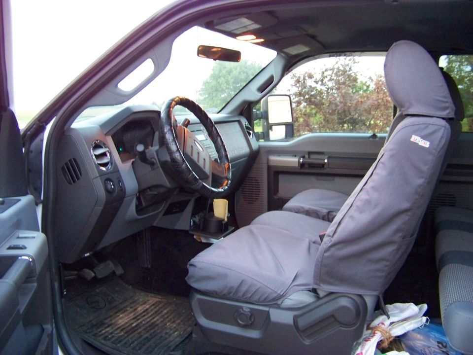 Interior of a truck, showing the dashboard, steering wheel, and seats with covers