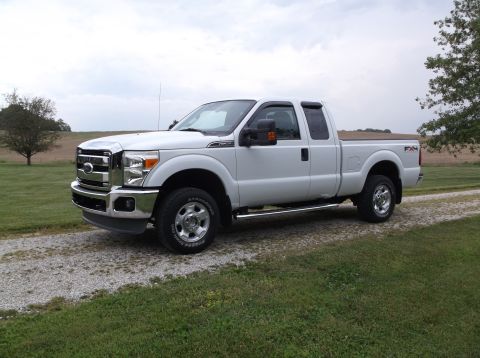 2011 Ford F-250 - White 2011 Ford F-250 pickup truck with chrome accents and FX4 badging is parked on a gravel road.