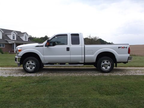2011 Ford F-250 - Side view of a white 2011 Ford F-250 pickup truck parked outside a house.