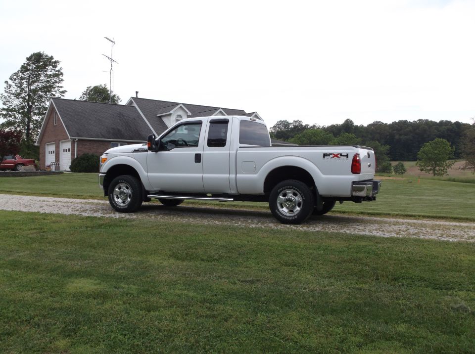 White Ford F-250 Super Duty pickup truck parked on a gravel driveway in front of a house