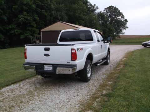 2011 Ford F-250 - This white Ford F-250 Super Duty pickup truck is parked on a gravel driveway next to a grassy area and a building.