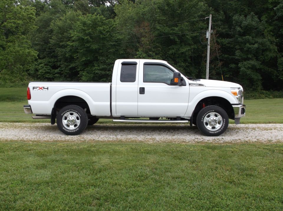 White 2011 Ford F-250 Super Duty pickup truck parked on a gravel driveway