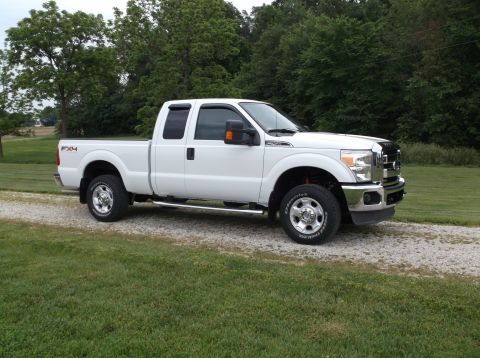 2011 Ford F-250 - This white Ford F-250 Super Duty pickup truck is shown from the front three-quarter view on a gravel driveway.