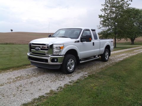 2011 Ford F-250 - A white Ford F-250 Super Duty truck is parked on a gravel driveway in a rural setting.