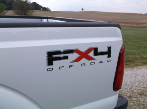 2011 Ford F-250 - Close-up of the FX4 OFF ROAD decal on the rear of a white pickup truck.