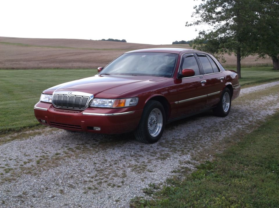 Red 1999 Mercury Grand Marquis parked on gravel driveway