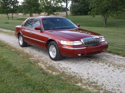 1999 Mercury Grand Marquis - Red 1999 Mercury Grand Marquis parked on a gravel driveway.