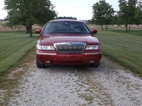 1999 Mercury Grand Marquis - This red Mercury Grand Marquis is parked on a gravel driveway with trees and a field in the background.