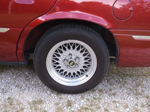 1999 Mercury Grand Marquis - Rear wheel of a red car with a BBS mesh style rim is visible.