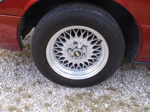 1999 Mercury Grand Marquis - A close-up shot focuses on a car's wheel and tire, with a BBS logo visible on the hub.