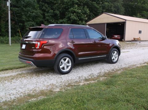 2016 Ford Explorer - A maroon Ford Explorer is parked on a gravel driveway next to a barn.