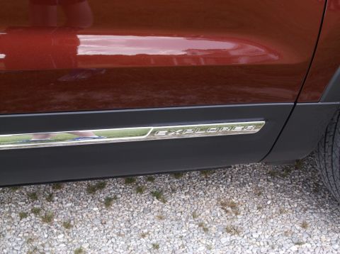2016 Ford Explorer - The side panel of a red SUV features black trim with the 'EXPLORER' nameplate.