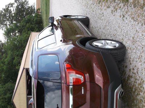 2016 Ford Explorer - A maroon SUV is parked on a gravel surface with a building in the background.