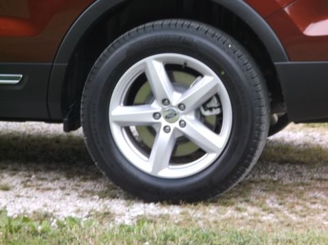 2016 Ford Explorer - A close-up view of a vehicle's wheel and fender flare, with the tire resting on gravel and grass.