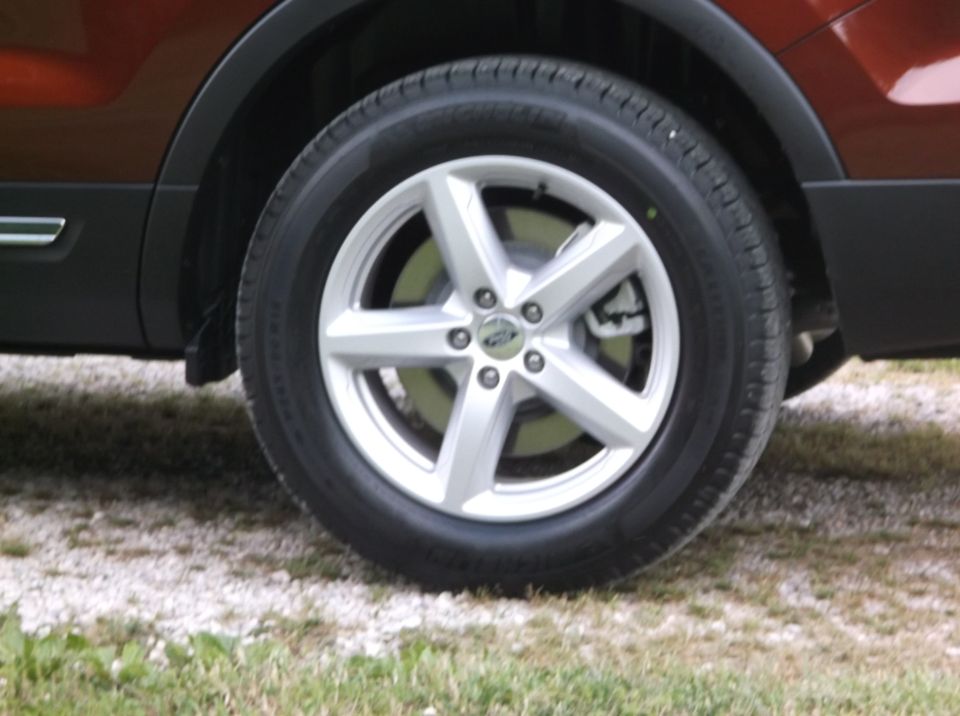 Close-up of a silver five-spoke wheel and part of a dark fender flare on a red vehicle