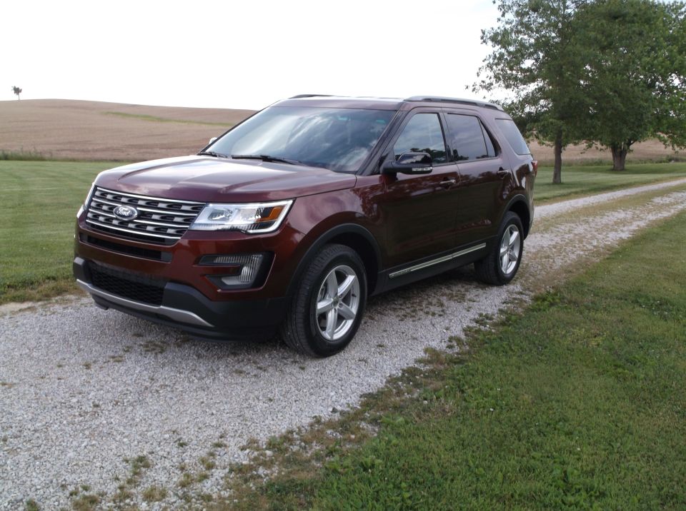 Maroon Ford Explorer parked on a gravel driveway next to a grassy field