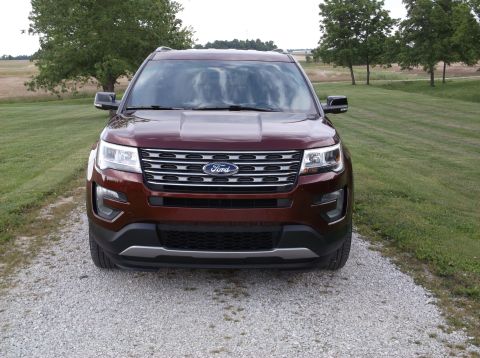 2016 Ford Explorer - This 2016 Ford Explorer is shown from the front, parked on a gravel driveway with grassy fields and trees in the background.