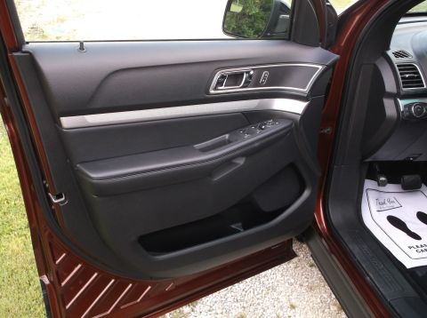 2016 Ford Explorer - Interior view of the driver's side door panel and floor mat in a maroon SUV.