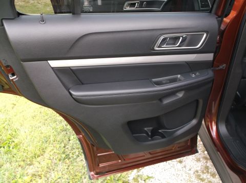2016 Ford Explorer - The interior door panel of a brown SUV features black leather trim and chrome accents, with a Supermotors.net watermark at the bottom.