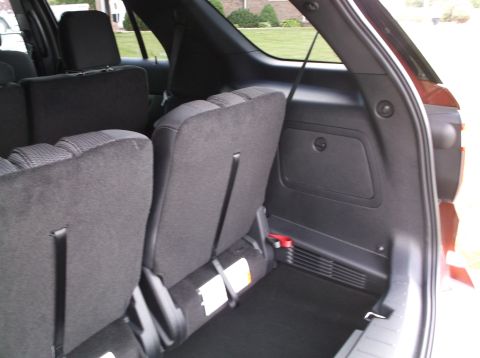 2016 Ford Explorer - The rear interior of an SUV shows folded seats and a spare tire, with no visible year-identifying features.