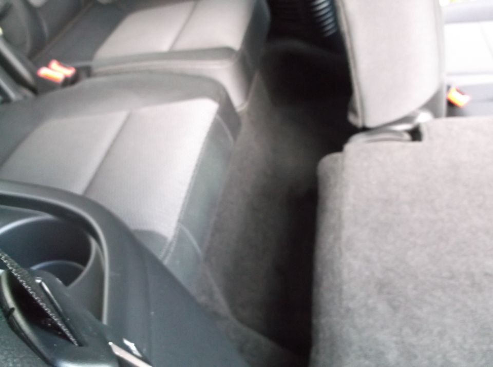 Rear seats and floor of a vehicle interior, showing dark grey fabric seats and carpet